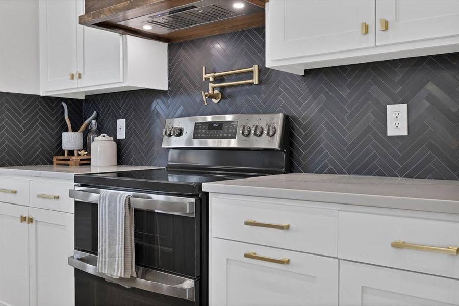 Kitchen featuring stainless steel electric range, premium range hood, white cabinetry, and backsplash Kitchen featuring stainless steel electric range, premium range hood, white cabinetry, and backsplash