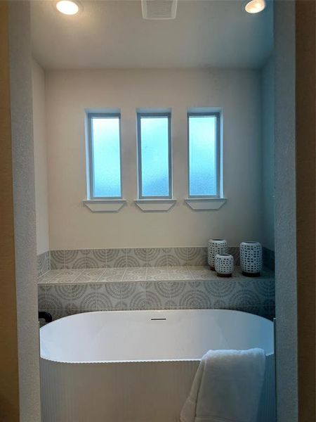 Modern freestanding tub set against a tiled wall with decorative patterns