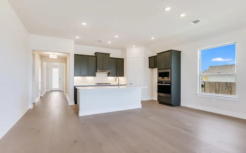 Kitchen with stainless steel appliances, recessed lighting, a center island with sink, light wood-style floors, and open floor plan
