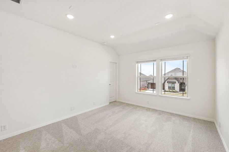 Empty bedroom with vaulted ceiling, carpet flooring, recessed lights, and a large window with neighborhood view