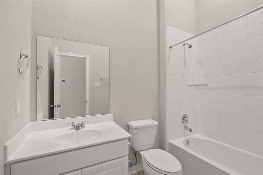 The secondary bath features tile flooring, white cabinetry and light countertops and a shower/tub combo. Perfect for accommodating any visiting family and friends.