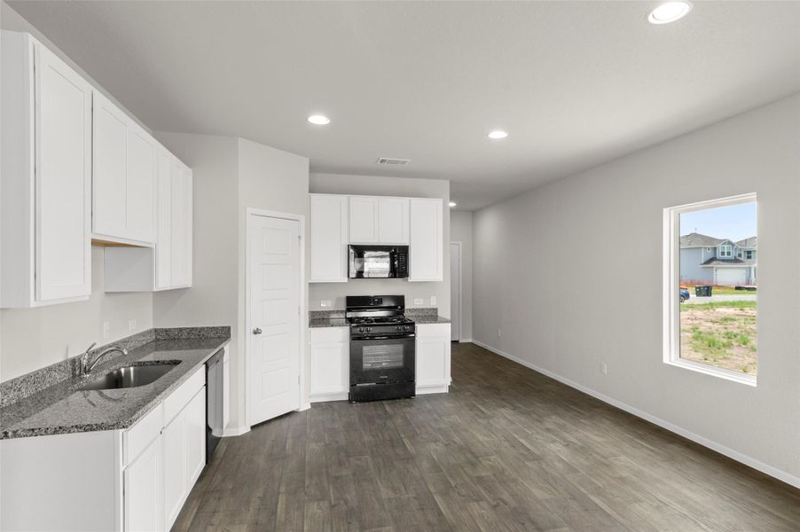 Kitchen with black appliances, recessed lighting, stone countertops, dark wood-style flooring, and white cabinetry Kitchen with black appliances, recessed lighting, stone countertops, dark wood-style flooring, and white cabinetry
