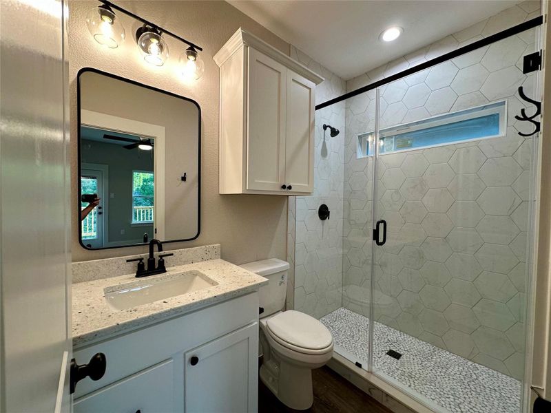 Bathroom featuring vanity, a stall shower, wood finished floors, and ceiling fan