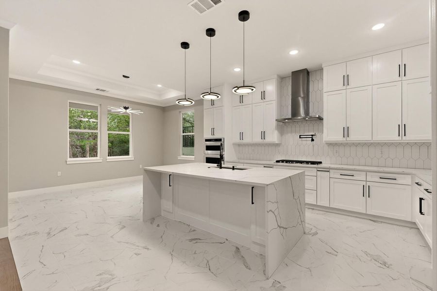 Kitchen with white cabinetry, quartz counters, a kitchen island with sink, hanging light fixtures, and recessed lighting Kitchen with white cabinetry, quartz counters, a kitchen island with sink, hanging light fixtures, and recessed lighting