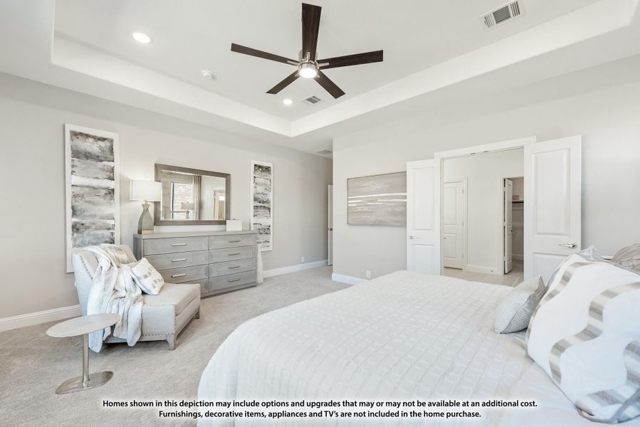 Spacious master bedroom with tray ceiling, ceiling fan, gray dresser, and neutral carpet flooring Spacious master bedroom with tray ceiling, ceiling fan, gray dresser, and neutral carpet flooring
