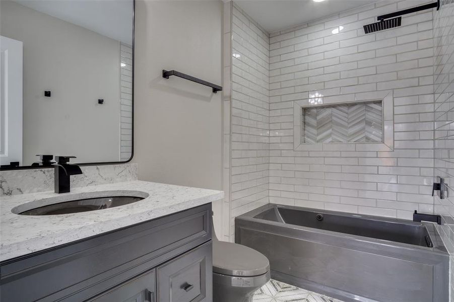 Bathroom with washtub / shower combination, toilet, and vanity