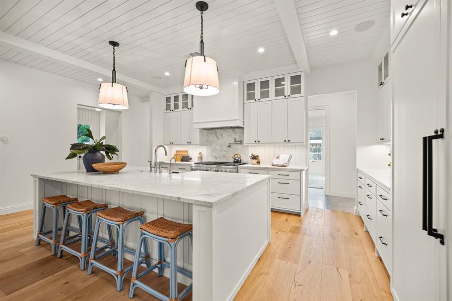 Kitchen featuring white cabinets, a large island, decorative light fixtures, and light hardwood / wood-style floors