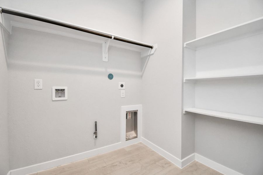 A perfect blend of functionality and comfort. Capture the essence of easy living with a first-floor laundry room, thoughtfully equipped with shelving for effortless organization. Both electric and gas connections available. Sample photo of completed home with similar floor plan. Actual colors and selections may vary.