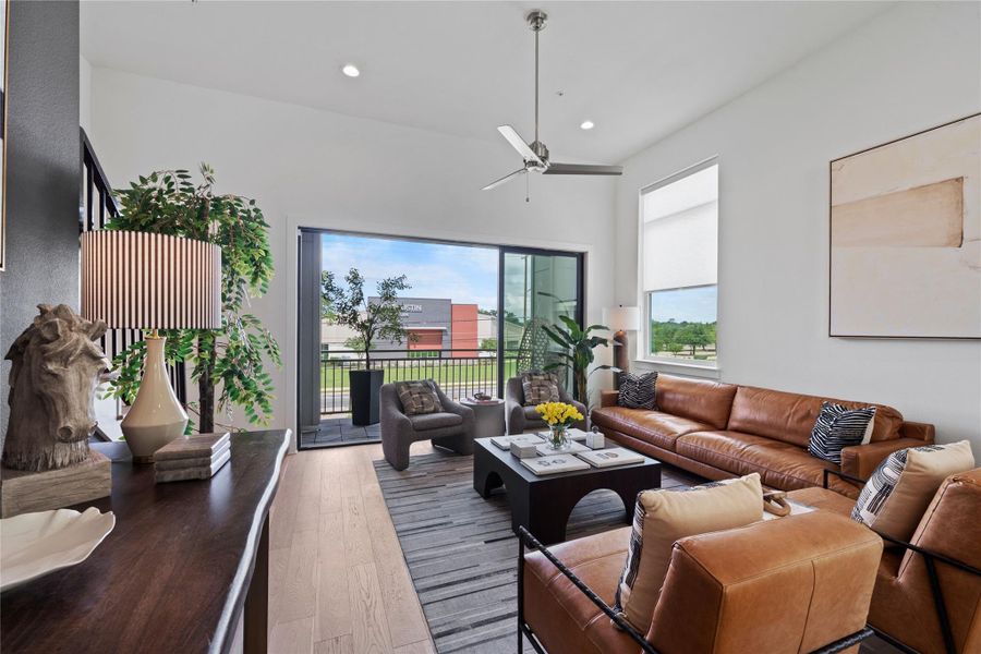 Open-concept living area with wood-finish flooring, high ceilings, and recessed lighting