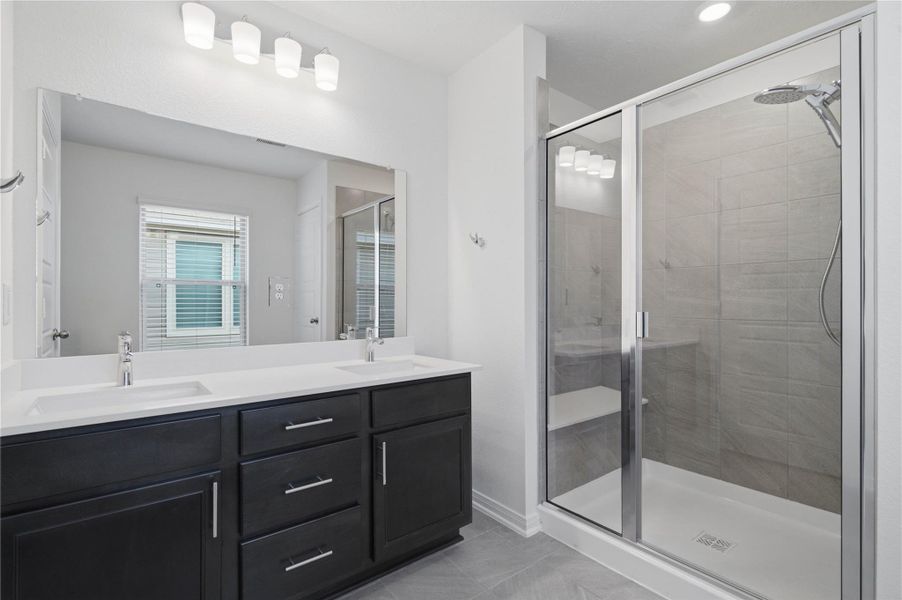 This stunningly updated primary bathroom is truly move-in ready! It features stained cabinetry with light countertops, dual sinks, a large mirror, large walk-in shower with built-in seat and tile surround, high ceilings, custom paint, and sleek modern finishes throughout.