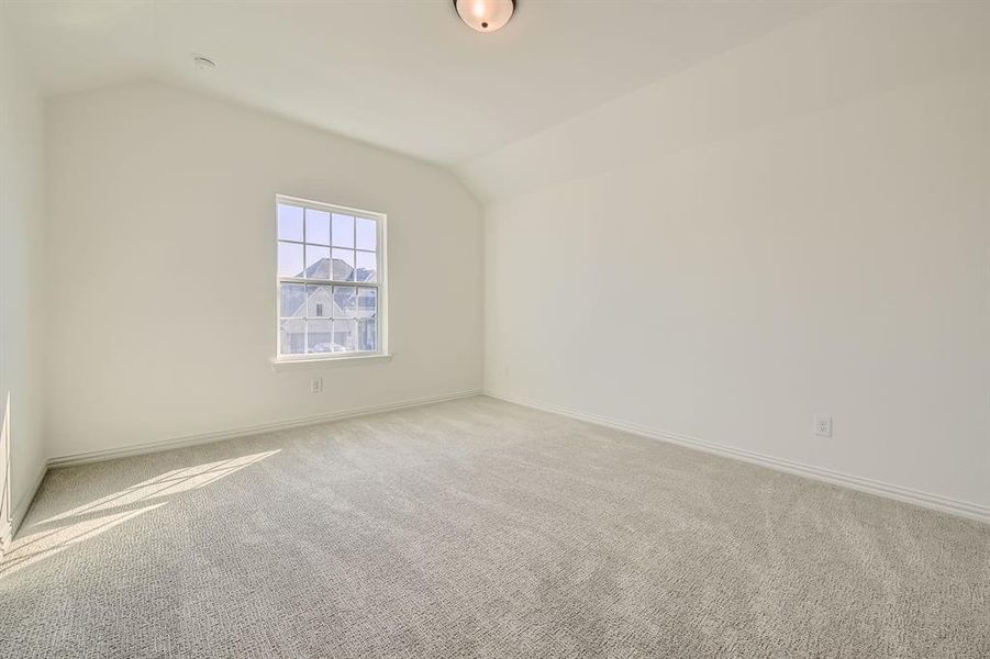 Spare room with vaulted ceiling and light colored carpet