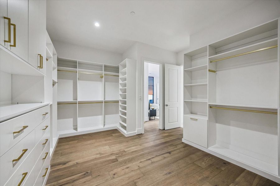 Positioned between the dual primary baths, this impressive walk-in closet features thoughtfully designed storage on all sides, providing exceptional functionality & a seamless connection between both spaces for ultimate convenience.