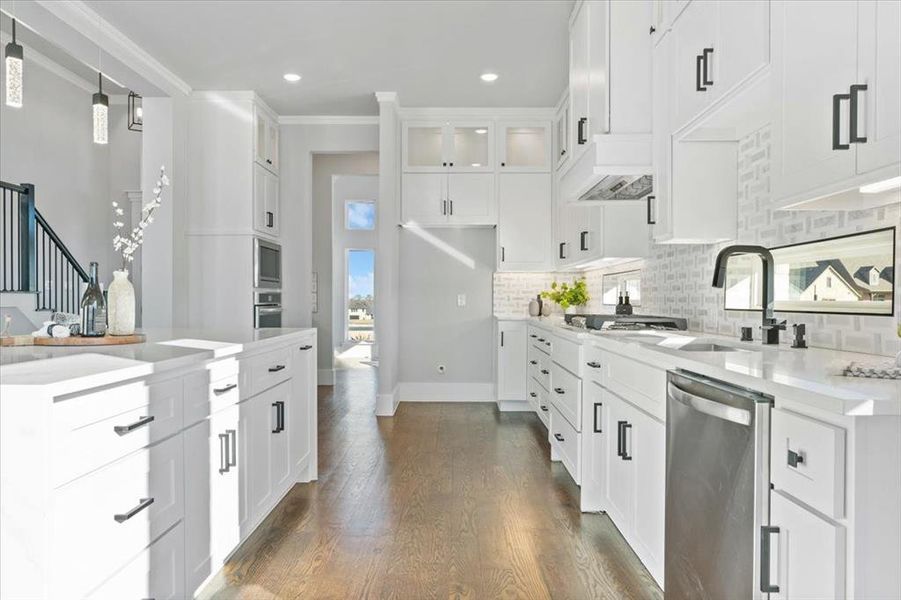 Kitchen with white cabinetry, ornamental molding, appliances with stainless steel finishes, dark hardwood / wood-style floors, and pendant lighting