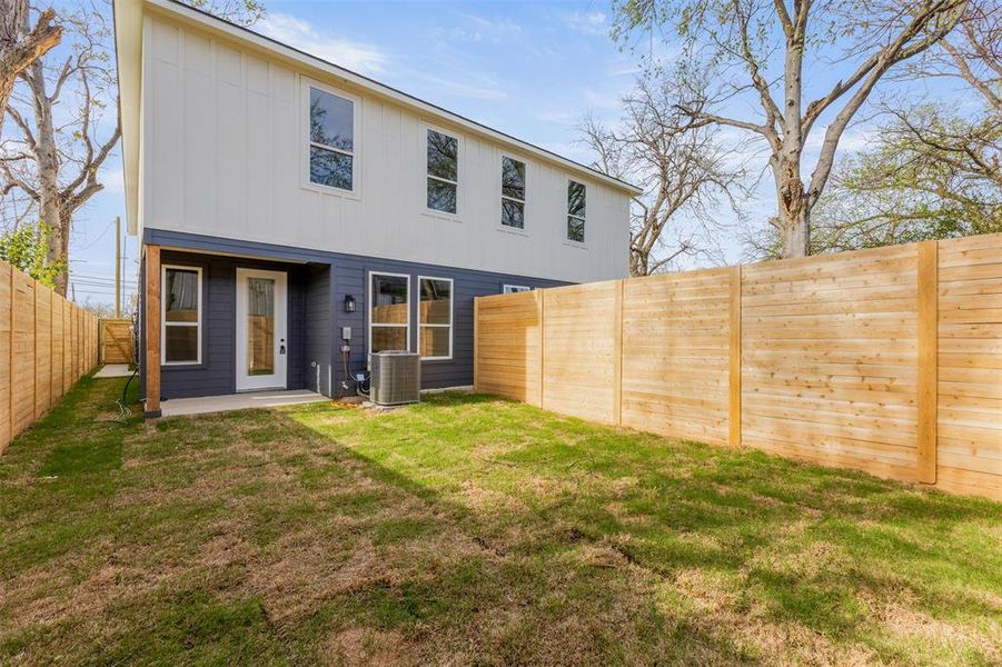 Back of house with board and batten siding, a fenced backyard, and a patio area