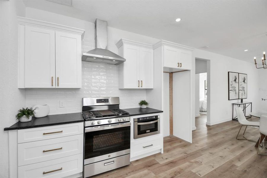 This is a utility closet featuring a tall, gray water heater with piping and venting installed against a white wall, with electrical outlets nearby. The space appears clean and well-maintained.