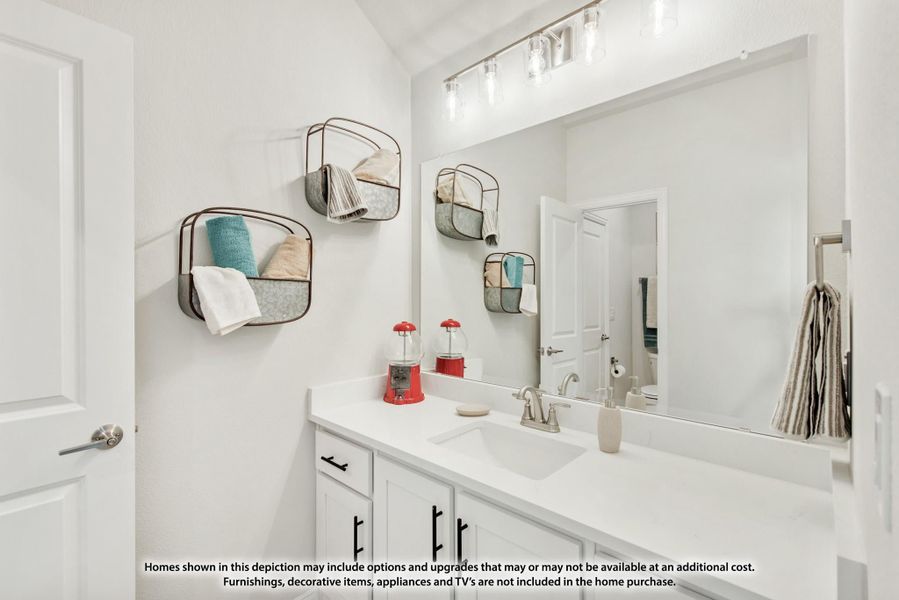 Bathroom with white vanity, large mirror, wall-mounted wire shelves, and lighted fixture above sink
