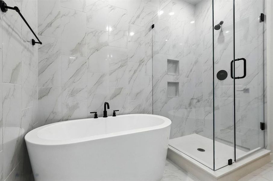 Full bath with a marble finish shower, a freestanding bath, marble tiled flooring, and tile walls Full bath with a marble finish shower, a freestanding bath, marble tiled flooring, and tile walls