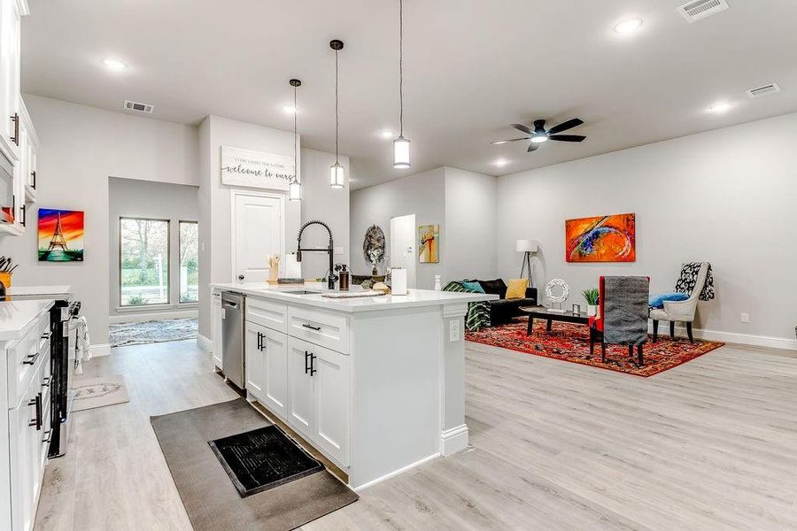 Kitchen with appliances with stainless steel finishes, sink, pendant lighting, a center island with sink, and white cabinets