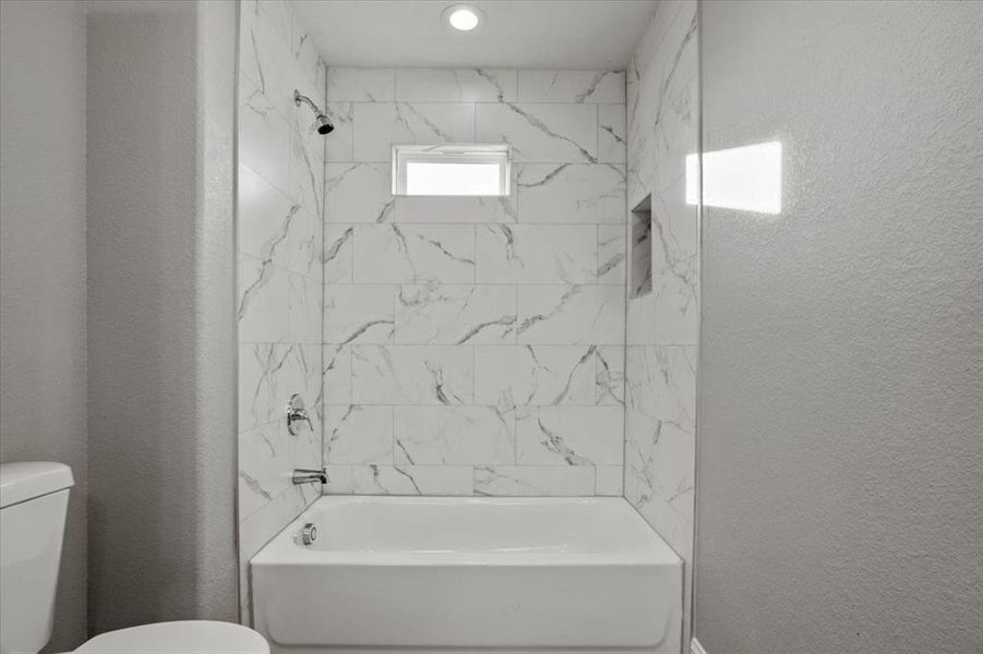 Bathroom featuring tiled shower / bath and toilet