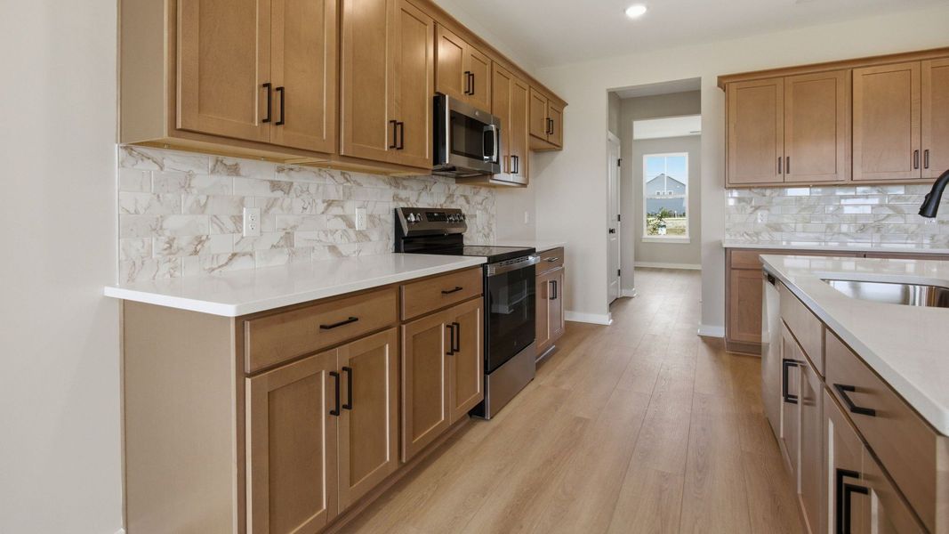 Kitchen with quartz countertops, tile backsplash, and view of flex room Kitchen with quartz countertops, tile backsplash, and view of flex room