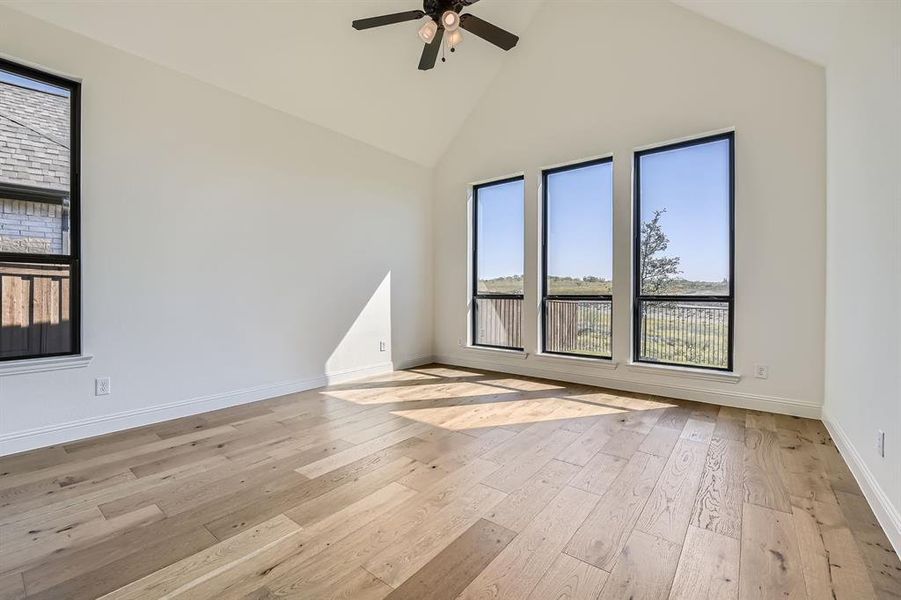 Spare room with ceiling fan, light wood-type flooring, and high vaulted ceiling