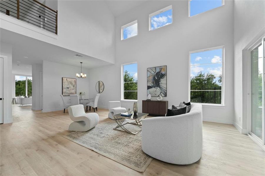 Living area with a chandelier, a towering ceiling, and light wood-style flooring Living area with a chandelier, a towering ceiling, and light wood-style flooring
