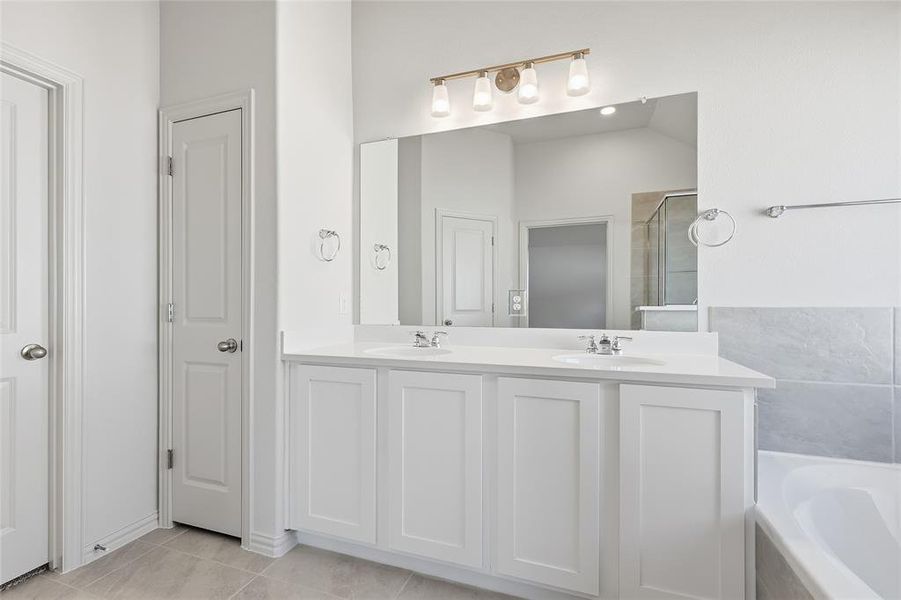 Bathroom featuring a bath, double vanity, light tile patterned floors, and a shower stall