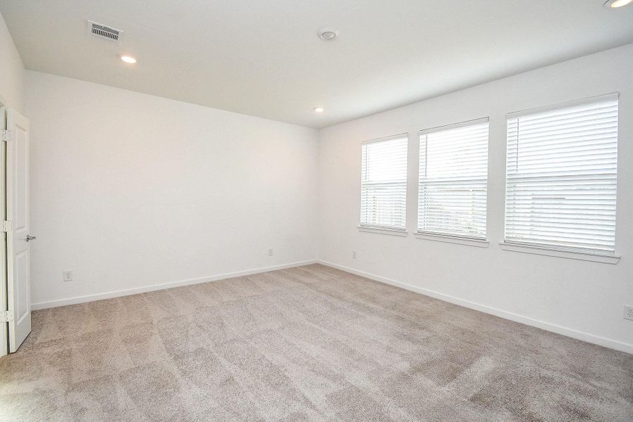 PRIMARY BEDROOM WITH WALL OF WINDOWS OVERLOOKING THE BACKYARD