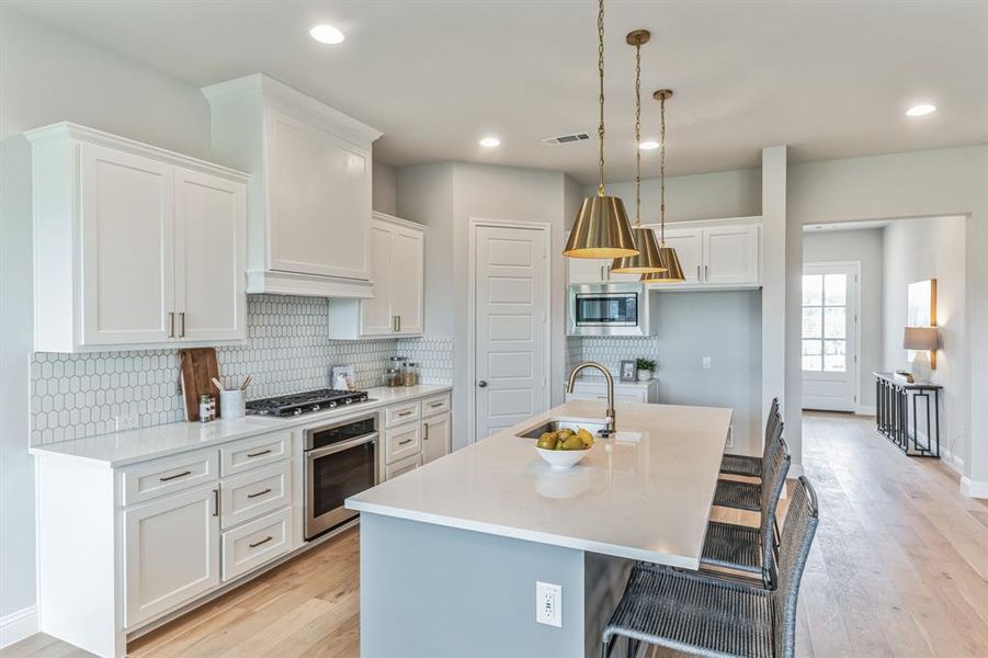 Kitchen featuring light hardwood / wood-style flooring, white cabinets, an island with sink, appliances with stainless steel finishes, and sink