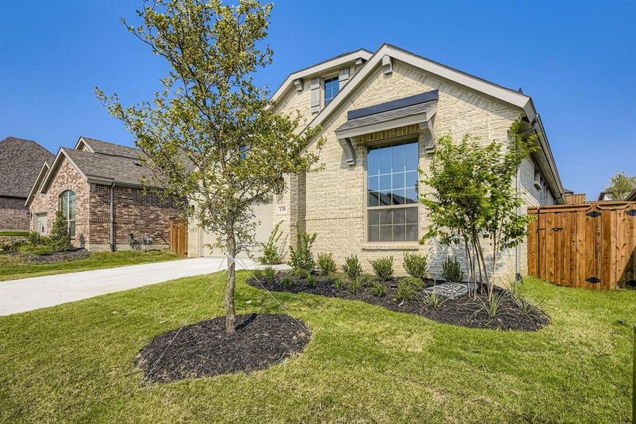 View of front of property with concrete driveway, a front lawn, brick siding, and a garage