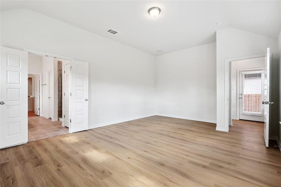 Unfurnished bedroom featuring light hardwood / wood-style floors and lofted ceiling