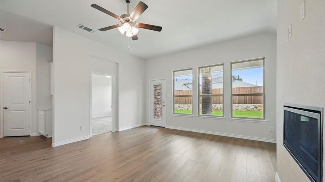 Spacious room featuring wood-finish flooring, a contemporary ceiling fan, and an integrated fireplace