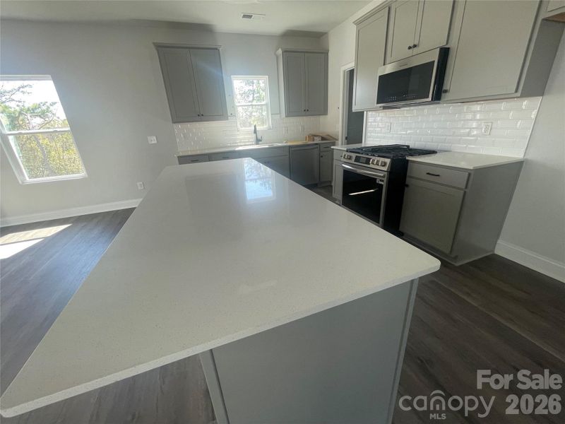 Quartz countertops in kitchen, subway tile backsplash, large  stainless steel sink, gas stove top and the microwave can even be used as an Air Fryer