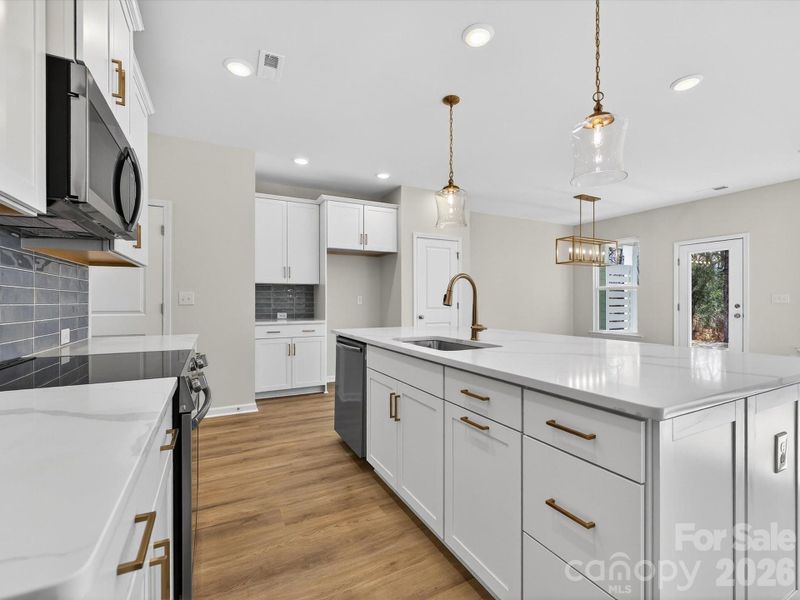 This bright and airy kitchen features an oversized kitchen Island. 42' kitchen cabinets with soft close doors & drawers. Solid shelving in the pantry. Stainless steel Frigidaire appliances with cooking vented to the outside.