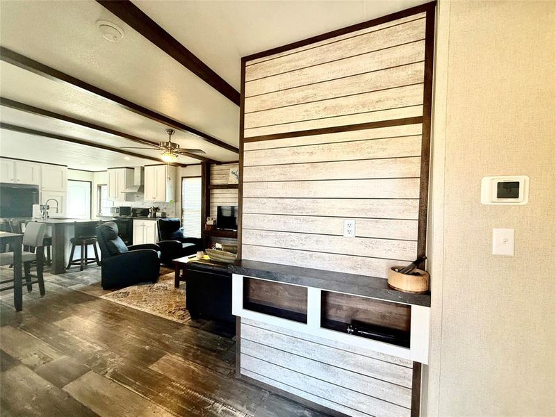 Living room with dark wood-style flooring, beamed ceiling, and a ceiling fan