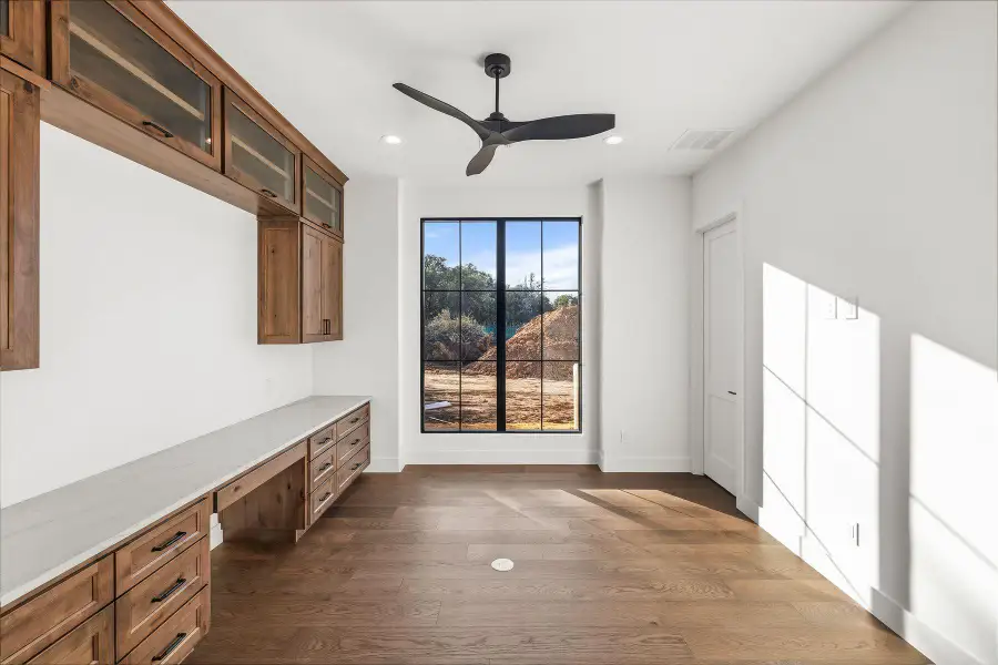 Unfurnished office with built in study area, ceiling fan, dark wood finished floors, and recessed lighting
