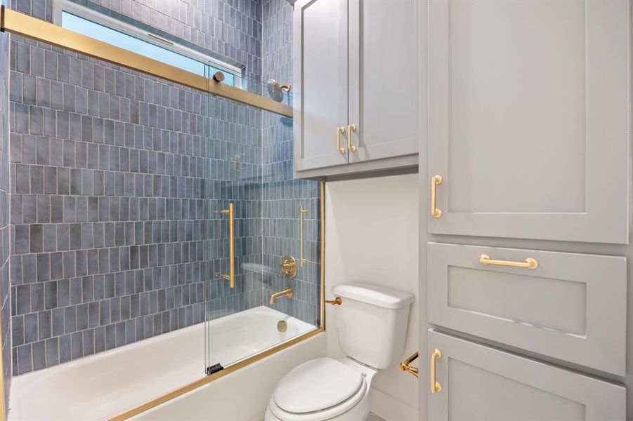 Bathroom featuring combined bath / shower with glass door and toilet