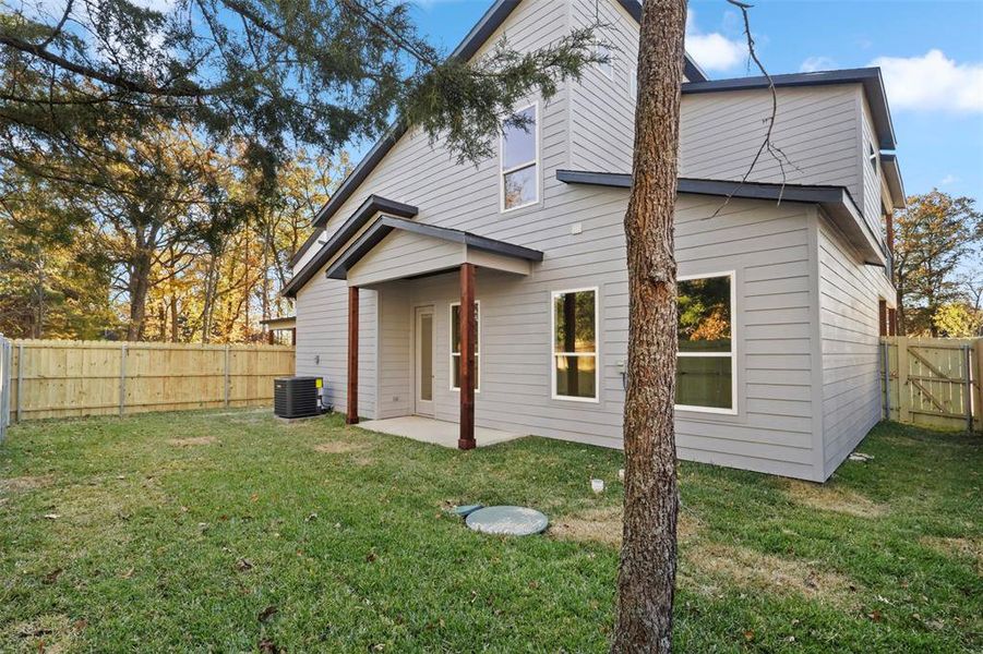 Back of property featuring a lawn, a patio area, and central AC