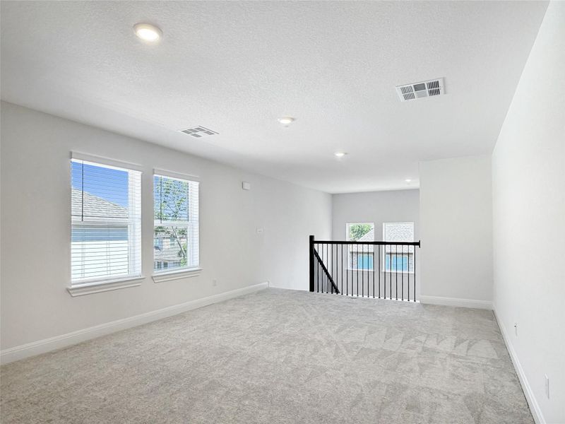 Upstairs flex space featuring plenty of natural light, light colored carpet, recessed lighting, and a textured ceiling