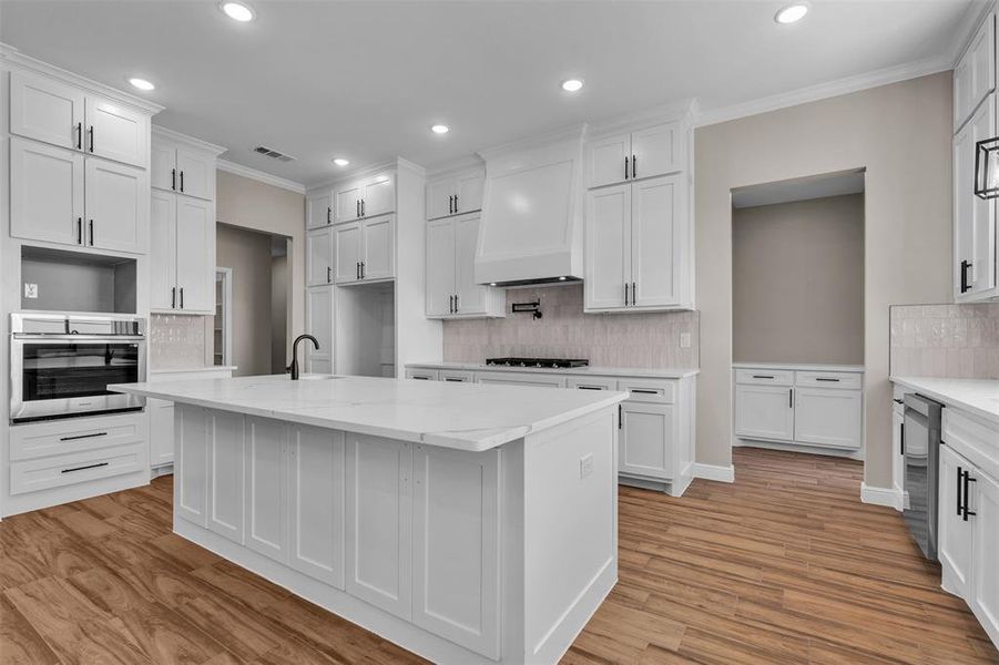 Kitchen with tasteful backsplash, ornamental molding, oven, recessed lighting, and white cabinets Kitchen with tasteful backsplash, ornamental molding, oven, recessed lighting, and white cabinets