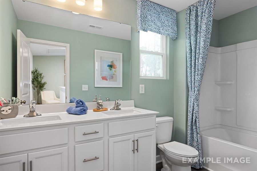 Full bathroom featuring shower / bath combination with curtain, vanity, and toilet