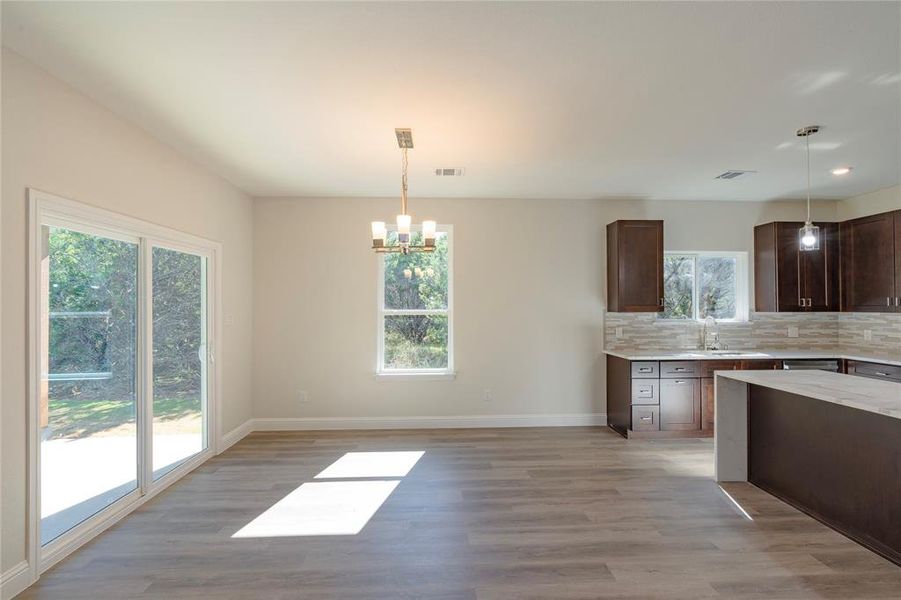 Kitchen with light wood-type flooring, a healthy amount of sunlight, and pendant lighting