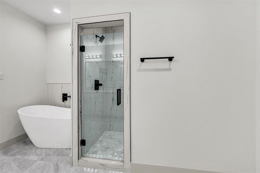 Full bathroom with a freestanding tub, marble look tile flooring, and a marble finish shower
