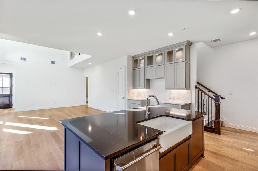 Kitchen featuring sink, light hardwood / wood-style floors, dishwasher, and a center island with sink