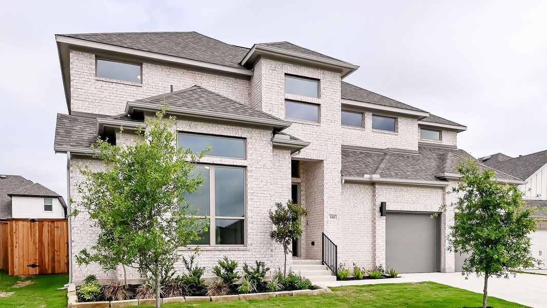 Prairie-style home featuring roof with shingles, fence, brick siding, driveway, and a garage