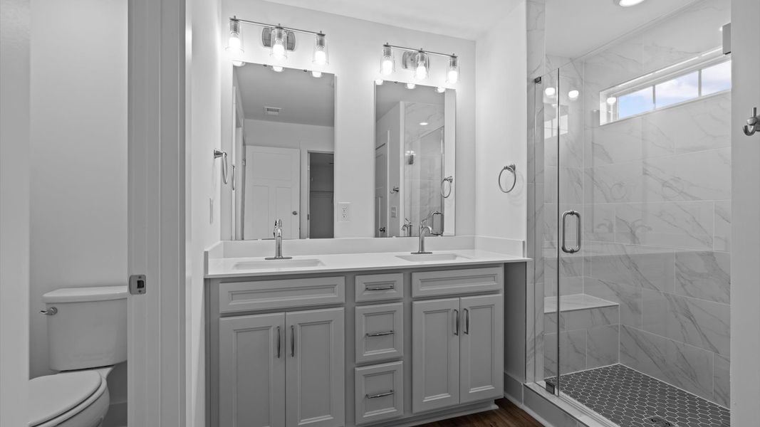 Highly functional and elegant en-suite with dual vanities, tiled walk-in shower, and refined finishes