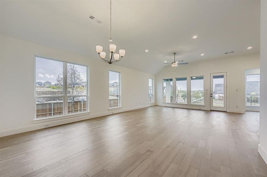 Unfurnished living room with recessed lighting, ceiling fan, light wood-type flooring, a chandelier, and lofted ceiling Unfurnished living room with recessed lighting, ceiling fan, light wood-type flooring, a chandelier, and lofted ceiling
