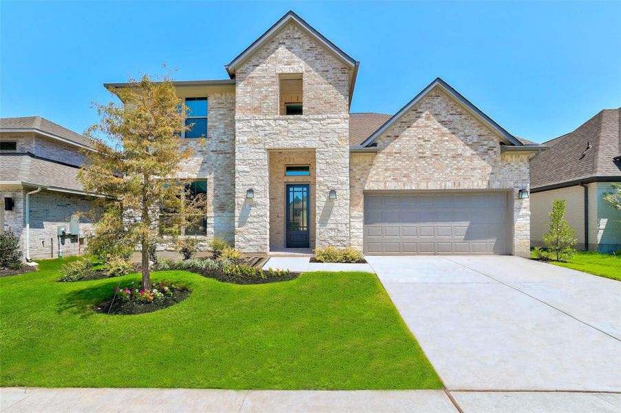 View of front facade featuring brick siding, driveway, a garage, a front lawn, and stone siding View of front facade featuring brick siding, driveway, a garage, a front lawn, and stone siding