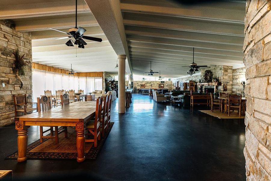 Dining room featuring a ceiling fan, finished concrete flooring, and beamed ceiling
