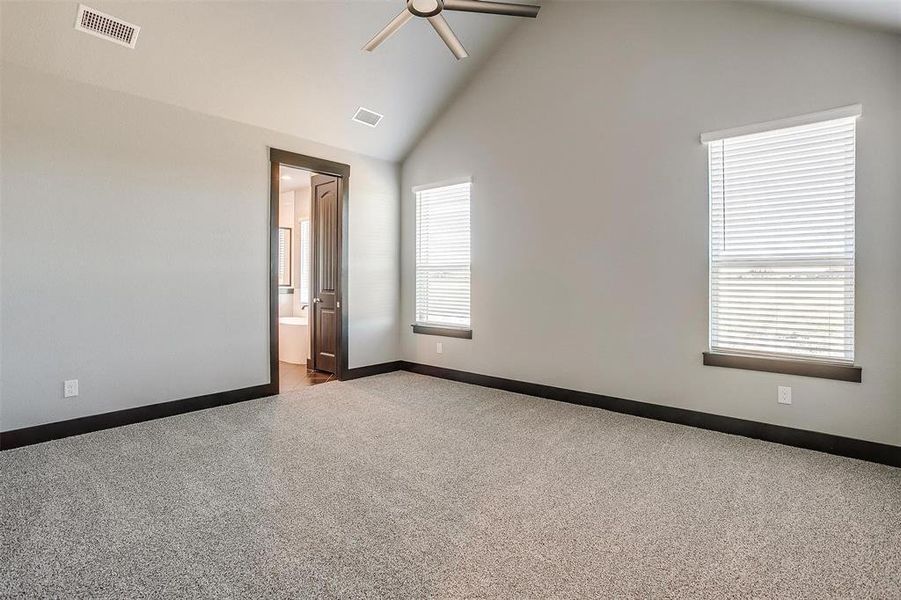 Empty room featuring ceiling fan, light colored carpet, a healthy amount of sunlight, and high vaulted ceiling